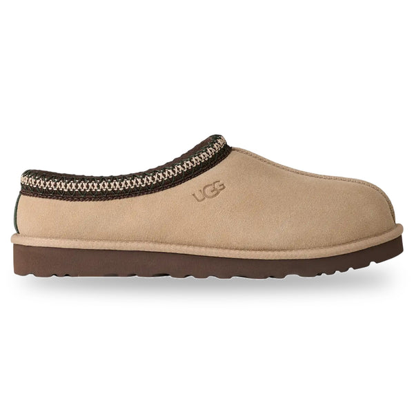 Beige UGG slipper with brown trim on a white background