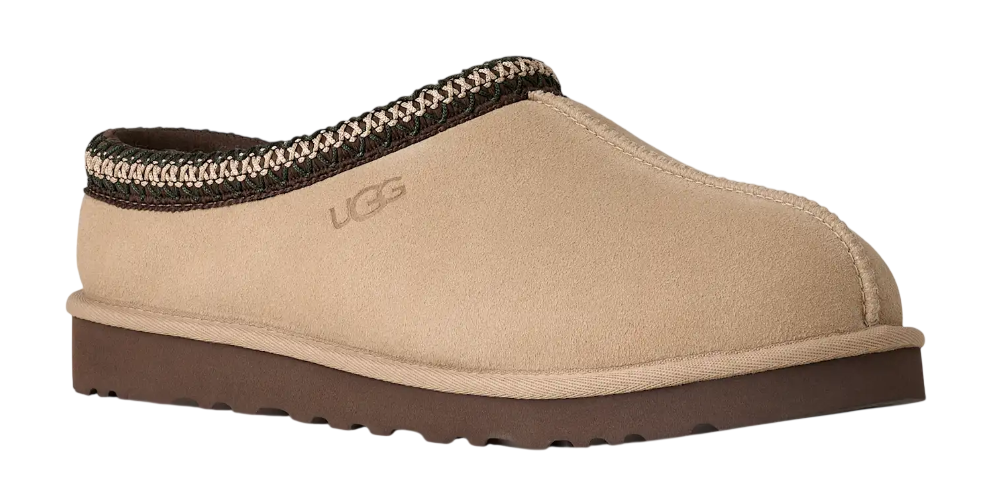 Beige UGG slipper with brown trim on a white background