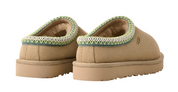 Pair of tan slippers with green trim on a white background