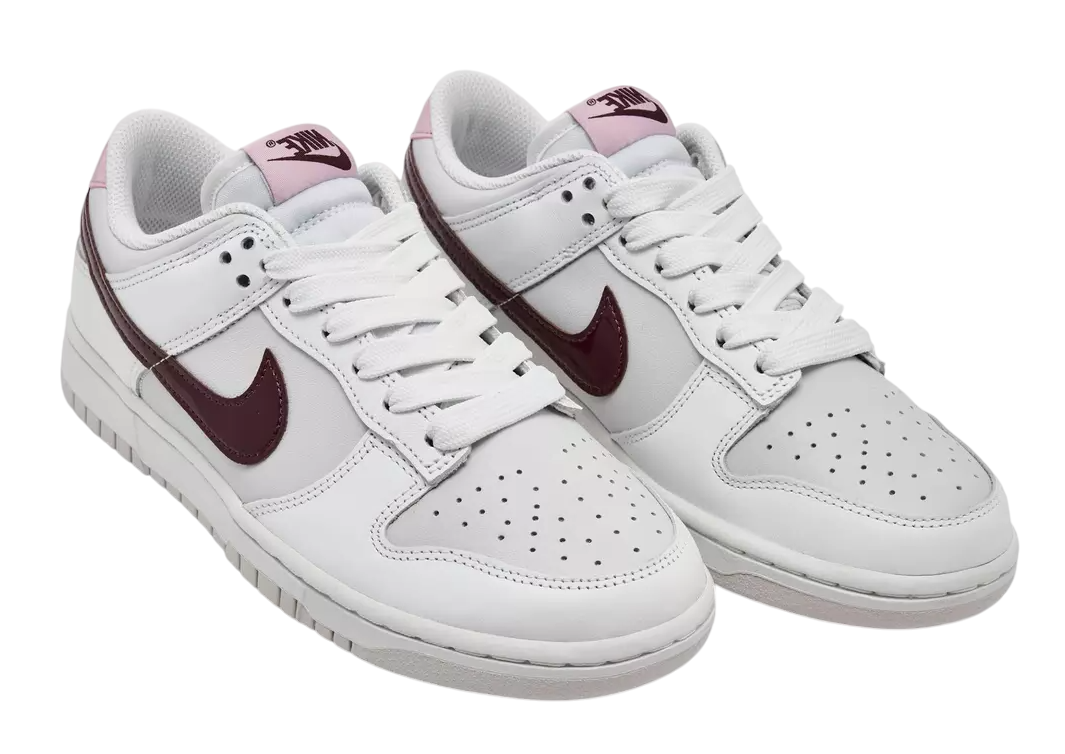 White sneakers with maroon swoosh logo on a white background
