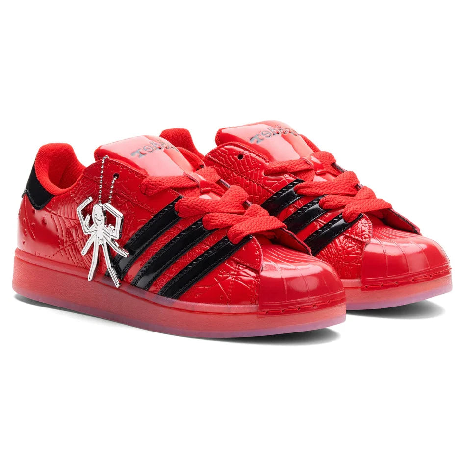 Red sneakers with black accents and a unique charm on a white background