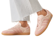 Pink sneakers with brown soles worn with light blue jeans on a white background