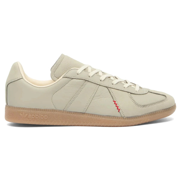 Beige Adidas sneaker with a red accent on a white background